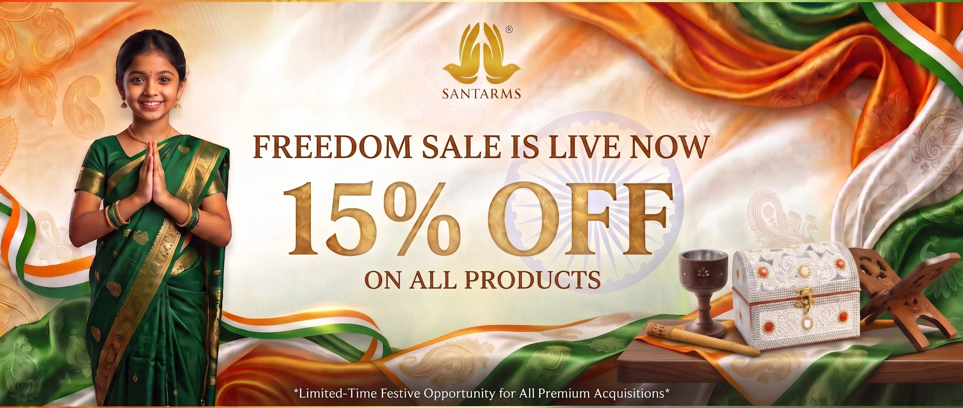 Promotional banner for Santarms featuring a woman in a green saree standing beside large sale text reading '15% OFF ON ALL PRODUCTS' and 'FREEDOM SALE IS LIVE NOW.' Decorative Indian flag colors and draped fabric appear around the text, with a small decorative box and a cup on a table at the lower right.
