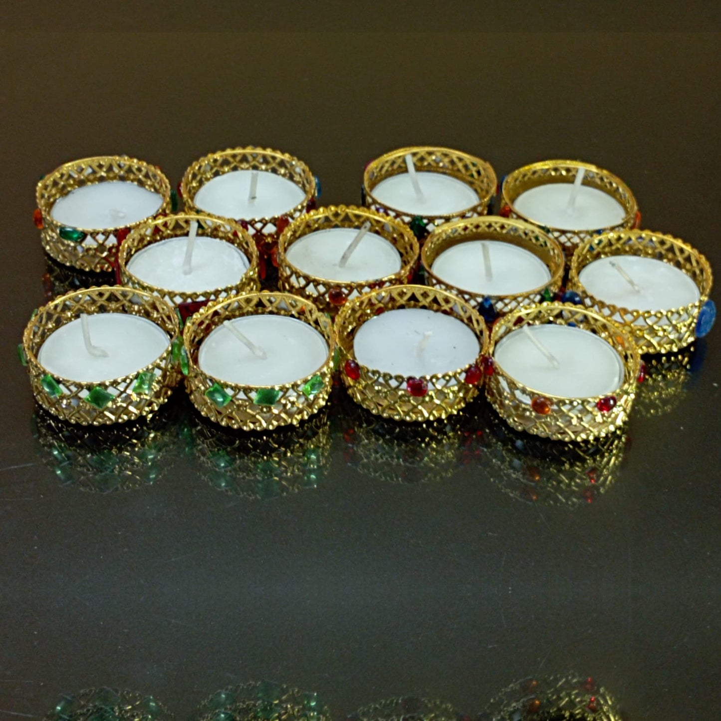 Gold candle holders with white candles on a reflective surface