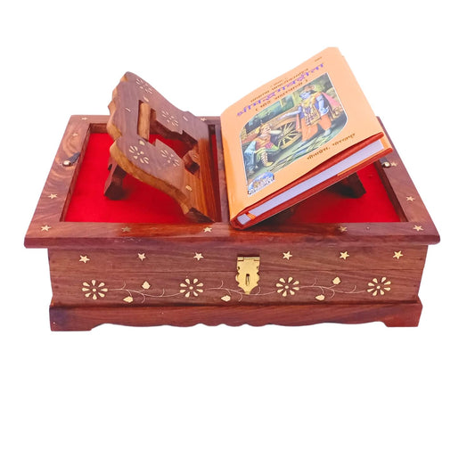 A wooden book-shaped music box with a red velvet-lined interior, decorated with gold-tone floral inlays and a latch. An open book rests inside as a prop, and the box is photographed on a plain white background.