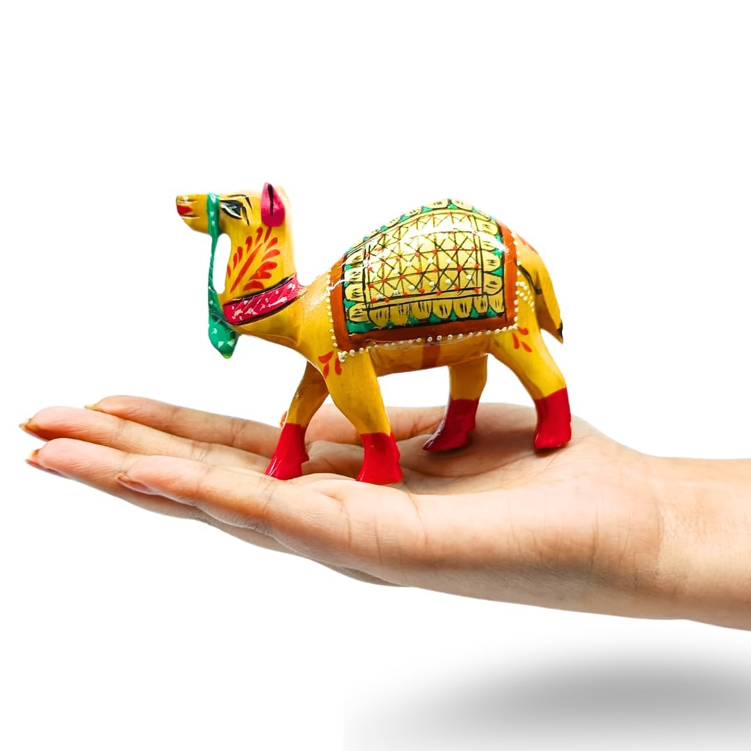 A small hand-painted camel figurine with yellow, green, red, and orange details, displayed on a person's open palm against a white background.