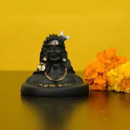 A black bust statue of Lord Shiva with gold jewelry and a white bird on his head, set against a yellow background with orange and yellow marigold flowers on the right.