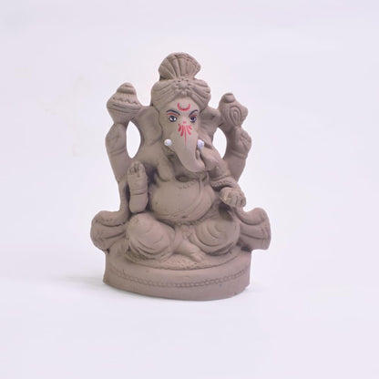 A small gray clay Ganesha statue with painted red and black facial details, seated on a round base against a plain white background.