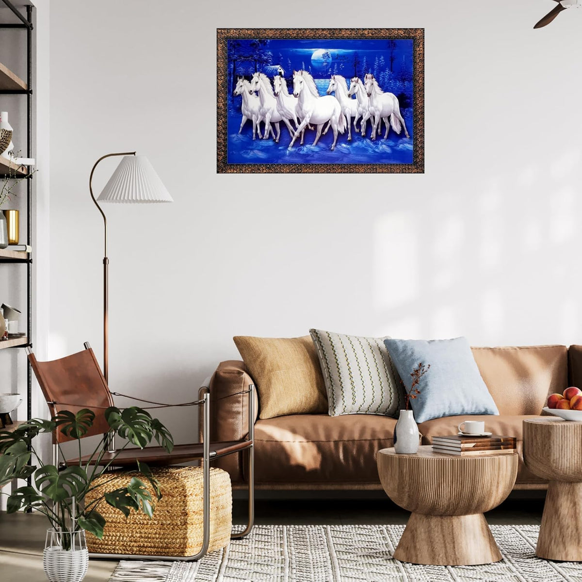 A framed wall art print depicting a group of white horses under a blue night sky, displayed above a brown leather sofa in a modern living room setting.