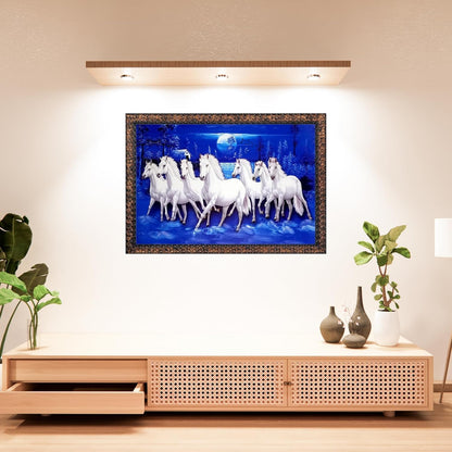 A framed wall art piece showing a group of white horses under a blue night sky, displayed above a light wood media console in a styled interior room.