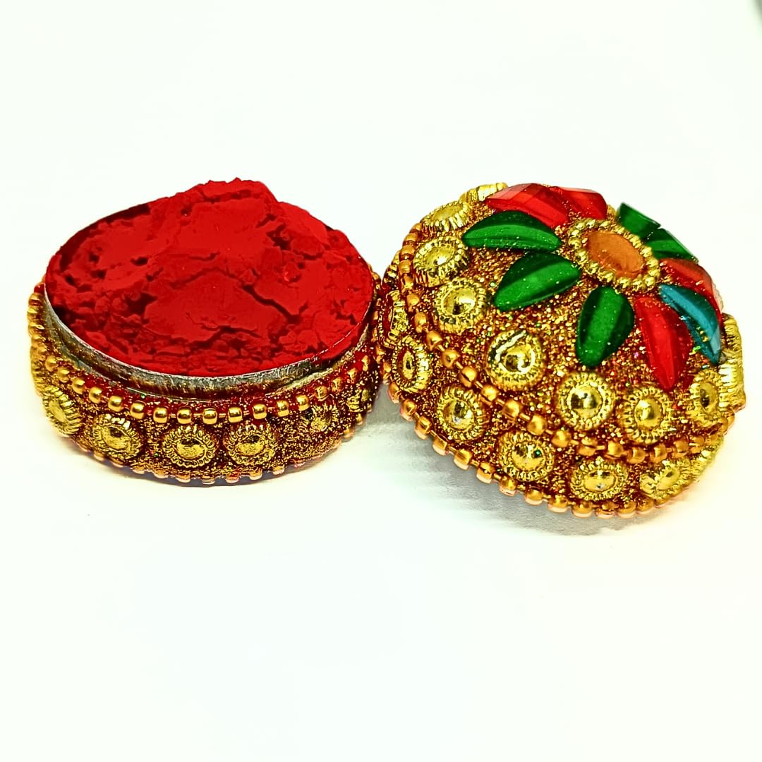 An ornate round decorative box shown open, with a bright red powder inside and a gold-toned lid decorated with red, green, and gold embellishments, on a plain white background.