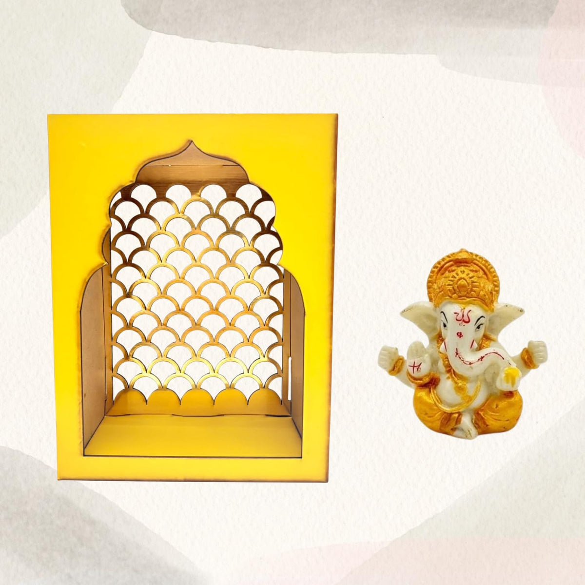 A yellow arched decorative wall niche with a scalloped cutout pattern, shown next to a small seated Ganesha figurine on a light textured background.