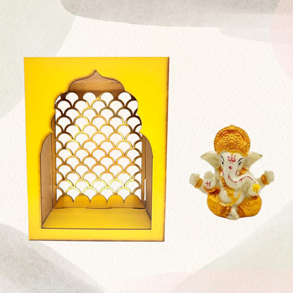 A yellow arched decorative wall niche with a scalloped cutout pattern, shown next to a small seated Ganesha figurine on a light textured background.