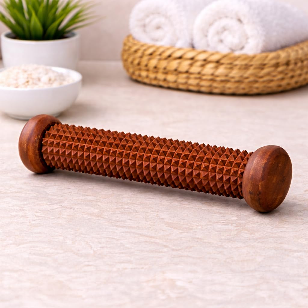 A wooden massage roller with a textured, diamond-patterned surface and rounded ends, resting on a light beige stone surface with spa props in the background.