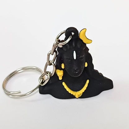 A black Shiva keychain featuring a molded black figure with yellow accents, including a crescent moon on the head, earrings, and necklace, attached to a silver split keyring on a plain white background.
