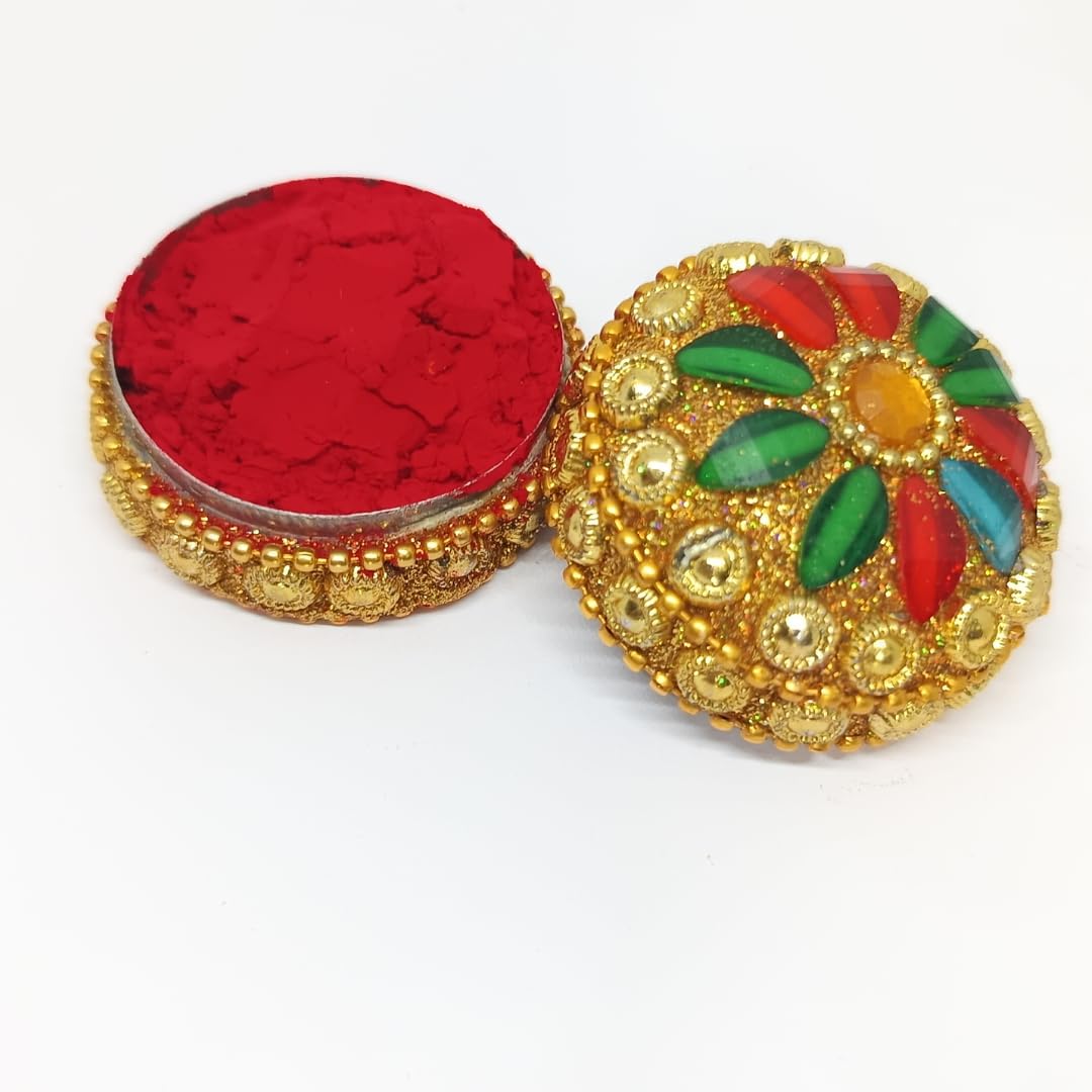 A decorative round box with a gold-tone ornate lid featuring multicolored floral inlays and a red powder or fabric lining shown open, photographed on a plain white background.